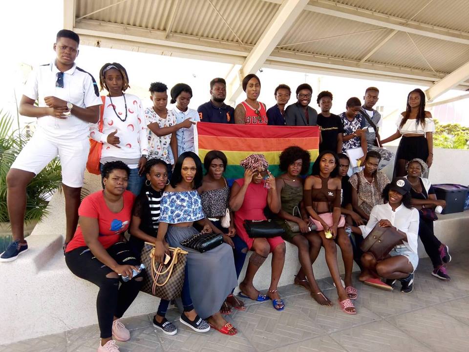 Des membres d'IRIS Angola posent tout au tour d'un drapeau arc-en-ciel.
