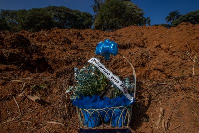 Un bouquet de fleur agrémenté de rubans bleus et du fanion "Repose en paix" sur une tombe fraichement creusée.