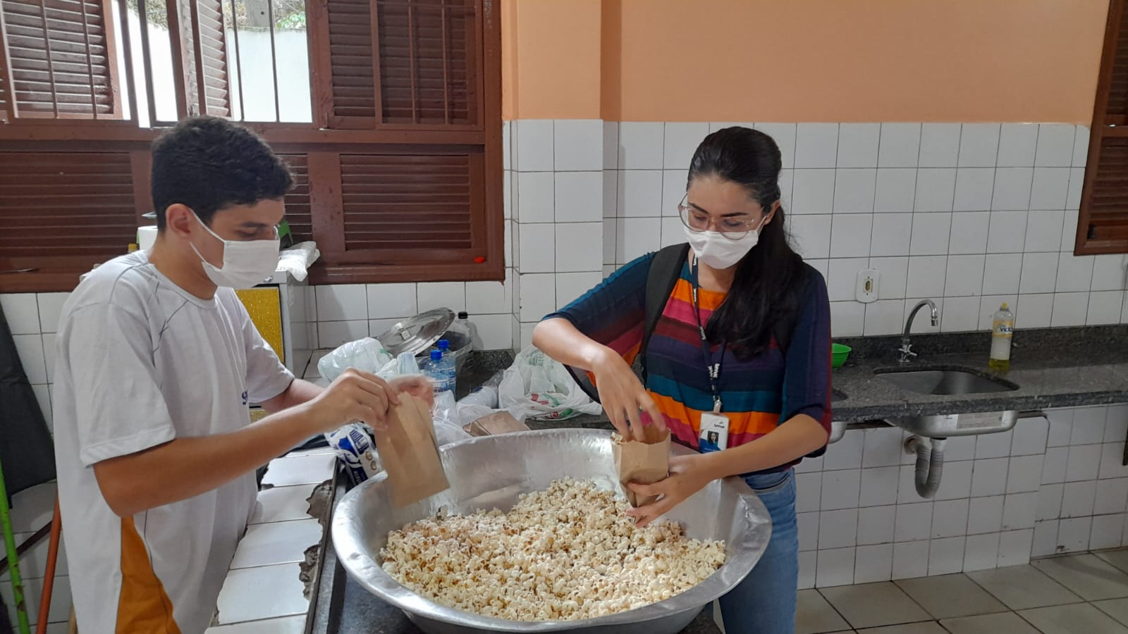 No abrigo, Roberto e outra voluntária preparam pipoca para as crianças | Imagem: Arquivo pessoal, utilizada com permissão