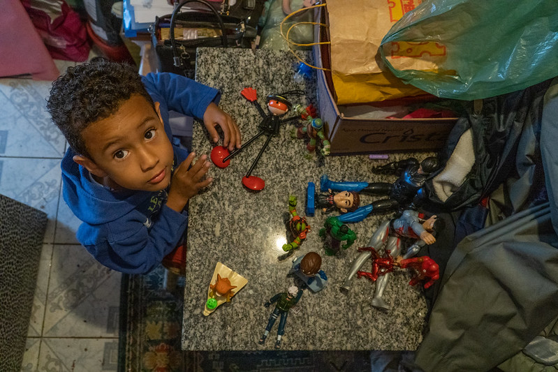 Petit garçon montrant ses figurines de jeux étalées sur une table.